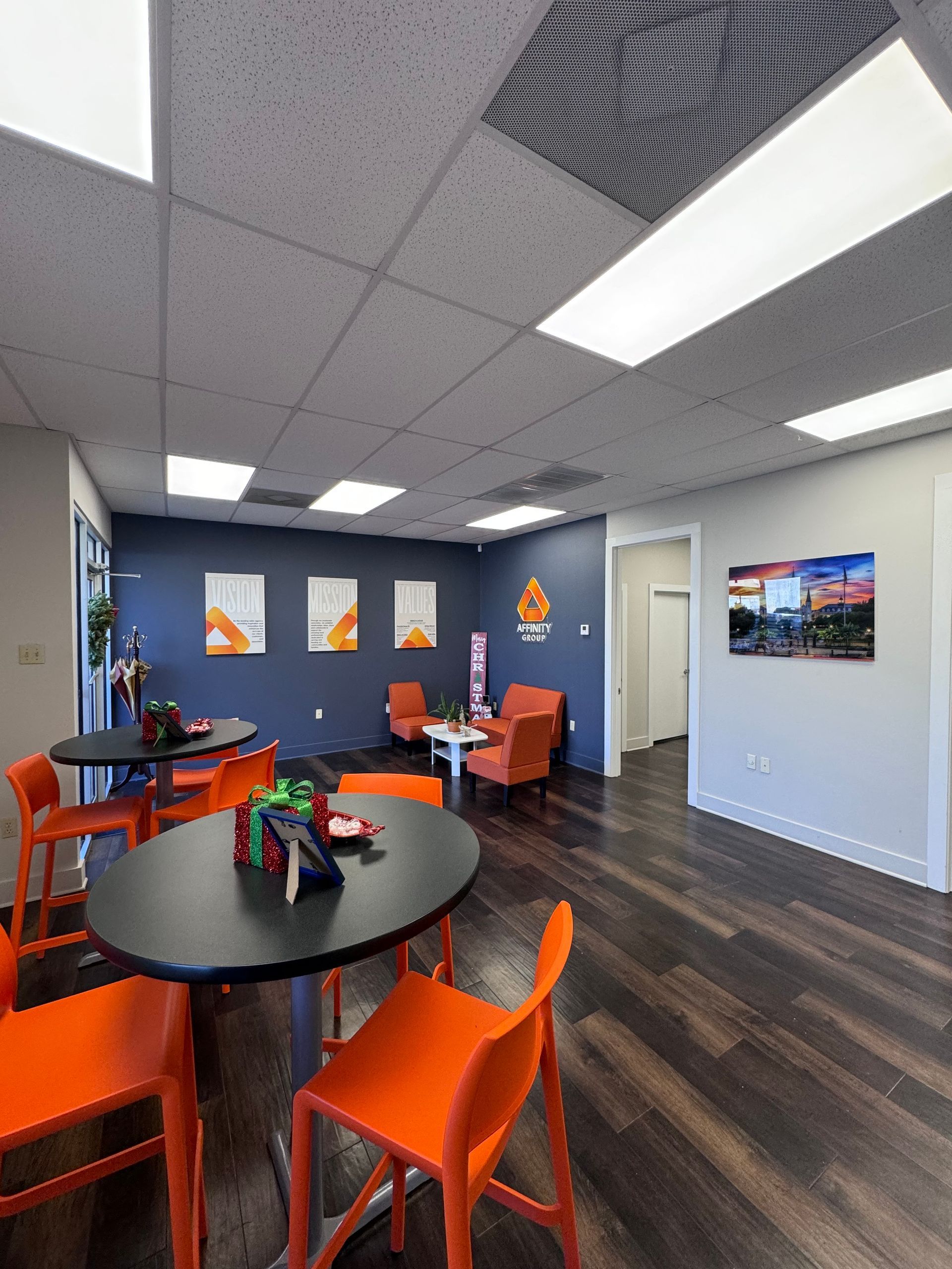 Modern lounge with orange chairs, black tables, and dark blue walls in an office break area