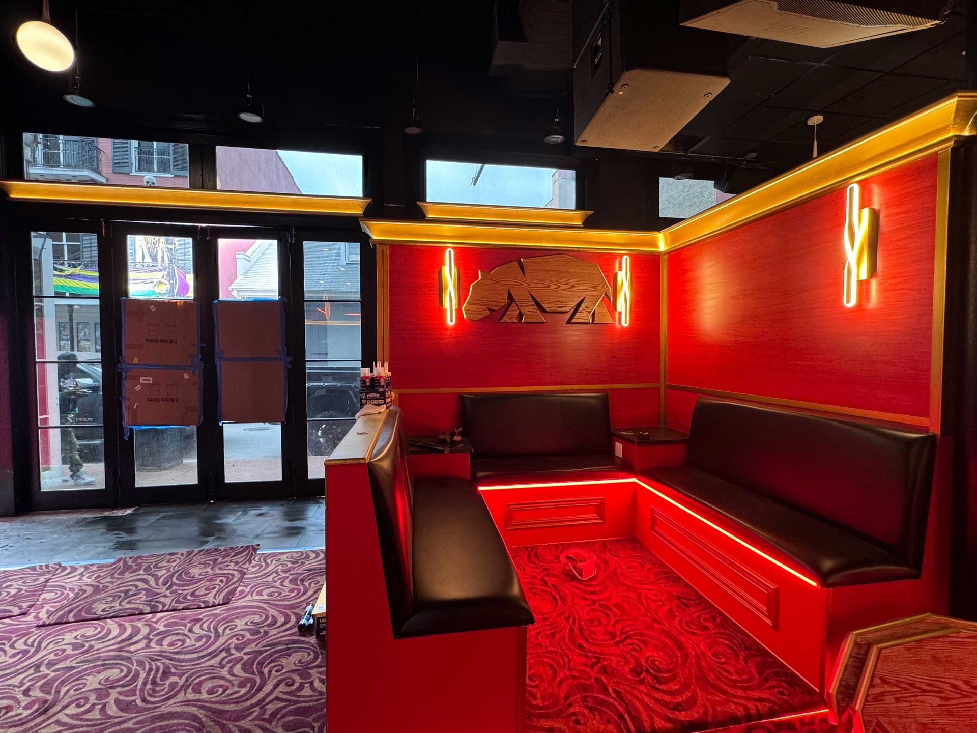 Red booth seating in an indoor setting with patterned carpeting, dim lighting, and a gold-accented wall with a bear motif.