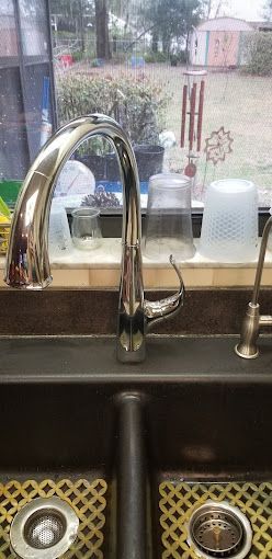 A kitchen sink with a faucet and a window in the background.