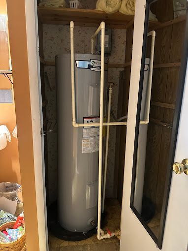 A water heater is sitting in a closet next to a mirror.