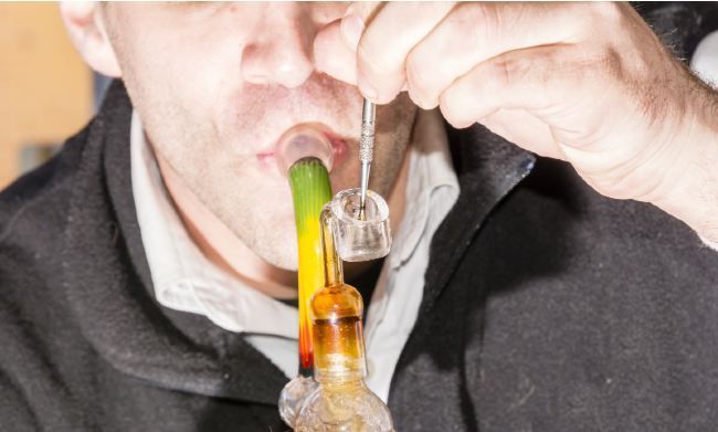 Person using a glass smoking device; taking a hit.
