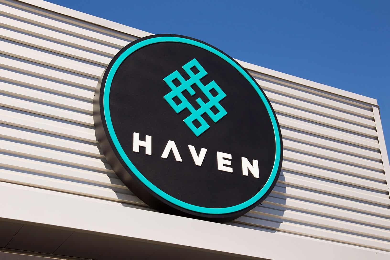 Round black sign with teal border and logo that says 