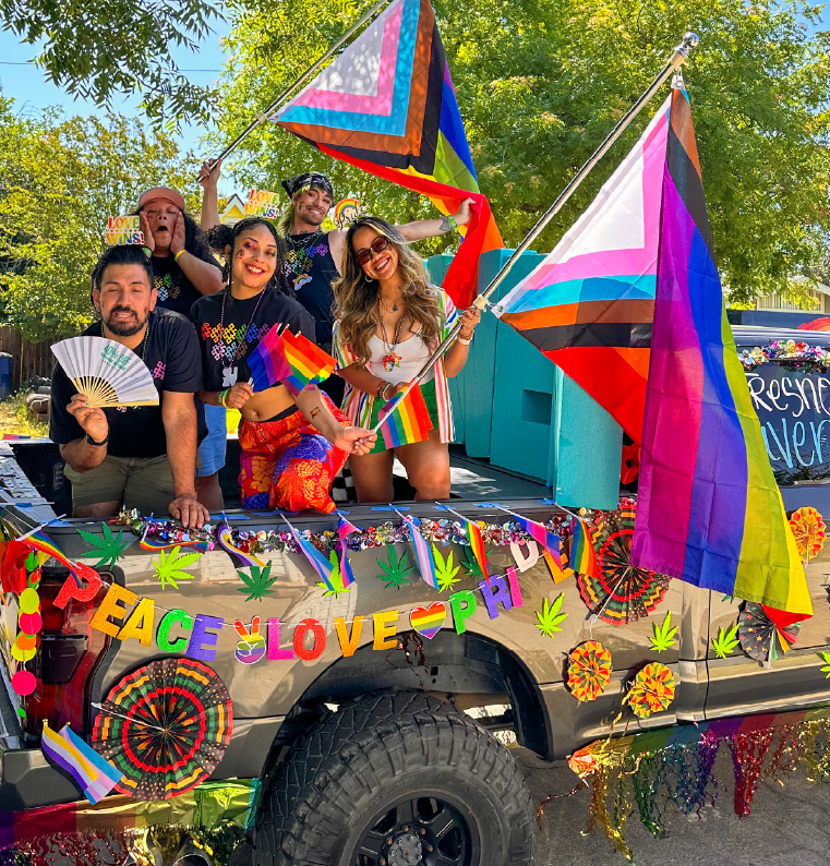 People on a decorated truck, waving Pride flags. 