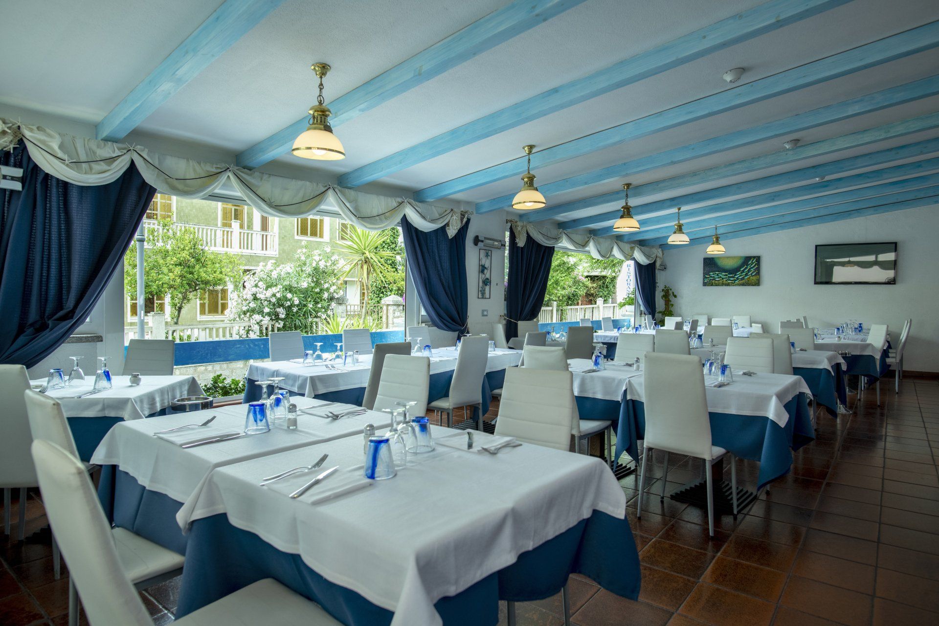 Un ristorante pieno di tavoli e sedie con tovaglie bianche e blu.