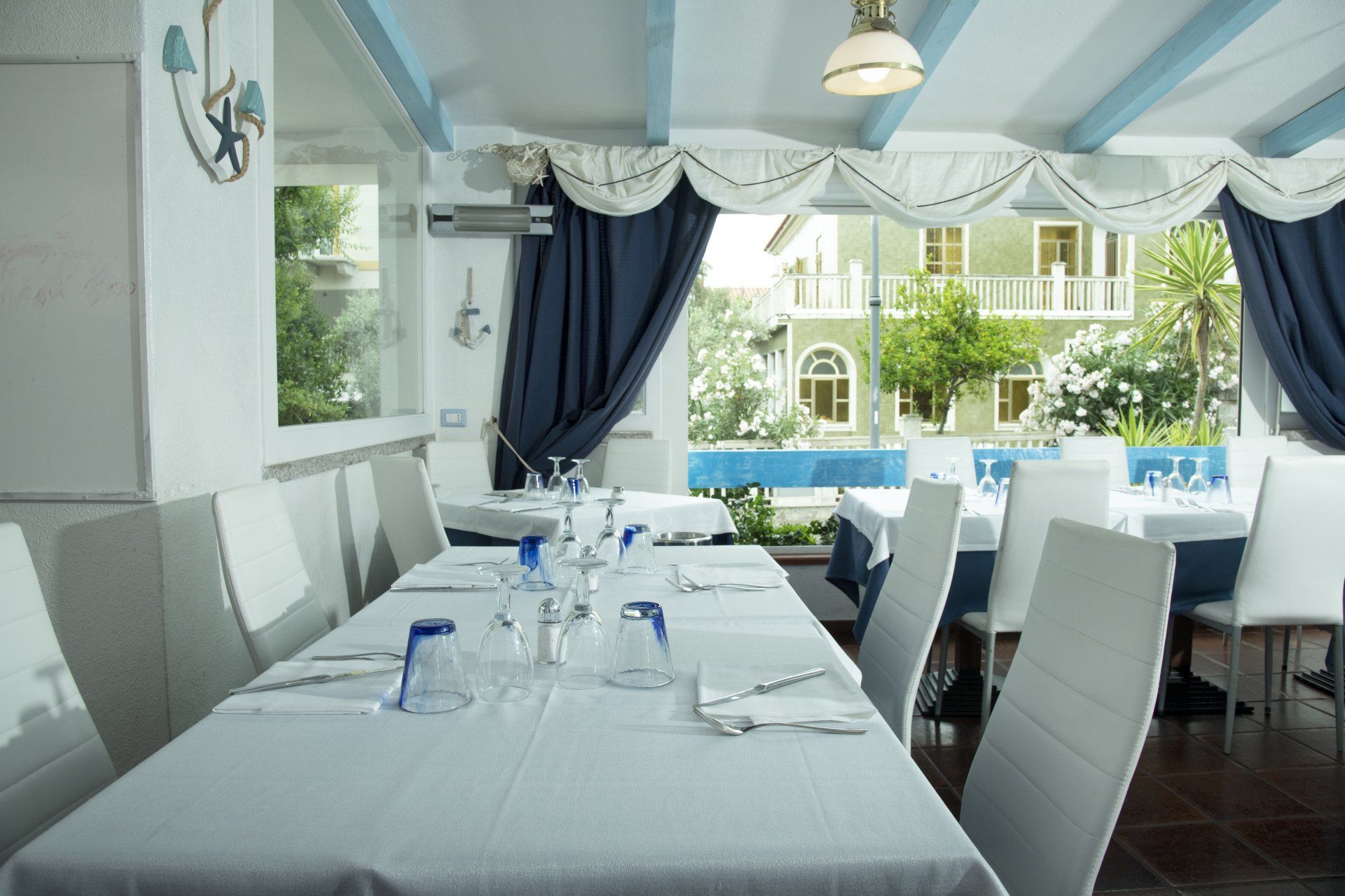 Una sala da pranzo con tavoli bianchi e tende blu