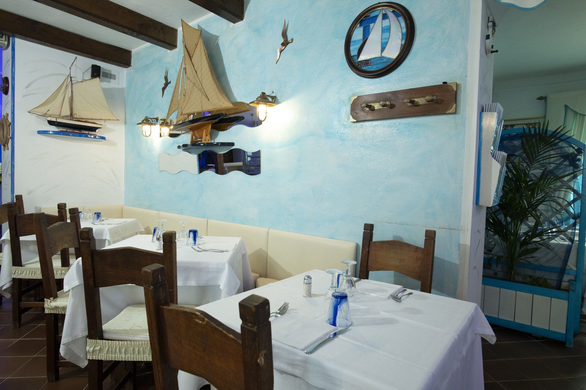 Una sala da pranzo con tavoli e sedie e una barca a vela alla parete