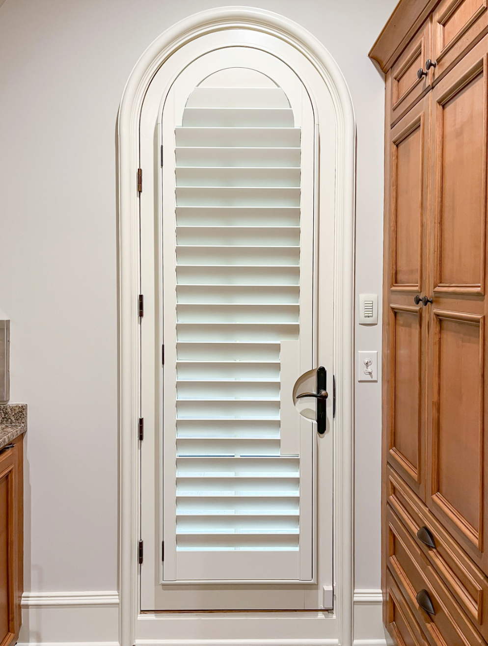 An arch top wood shutter with a door handle cutout