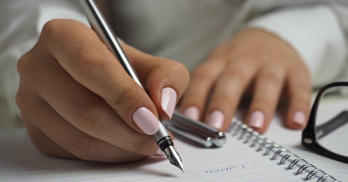 A woman is writing in a notebook with a fountain pen.