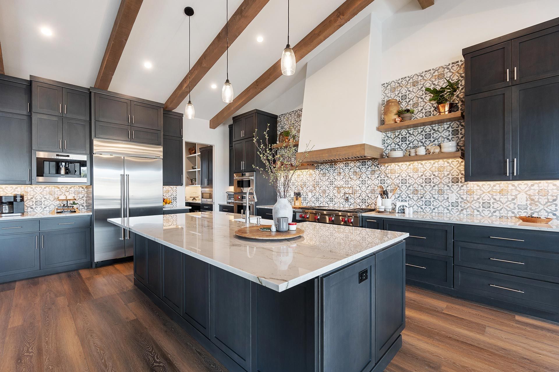 Spacious modern kitchen with dark cabinets, marble island, and patterned tile backsplash. Spacious modern kitchen with dark cabinets, marble island, and patterned tile backsplash.