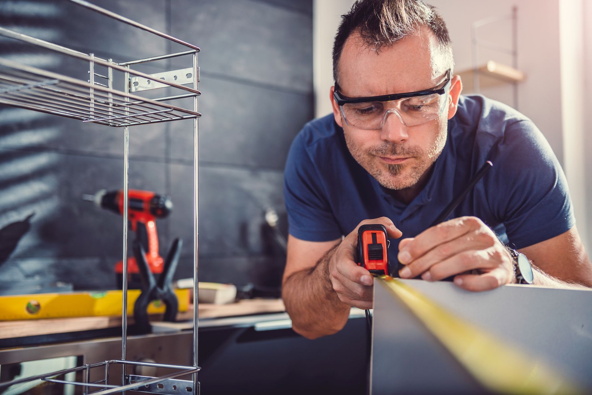 Man installing kitchen cabinets using drill and clamps in bright modern kitchen. Man installing kitchen cabinets using drill and clamps in bright modern kitchen.