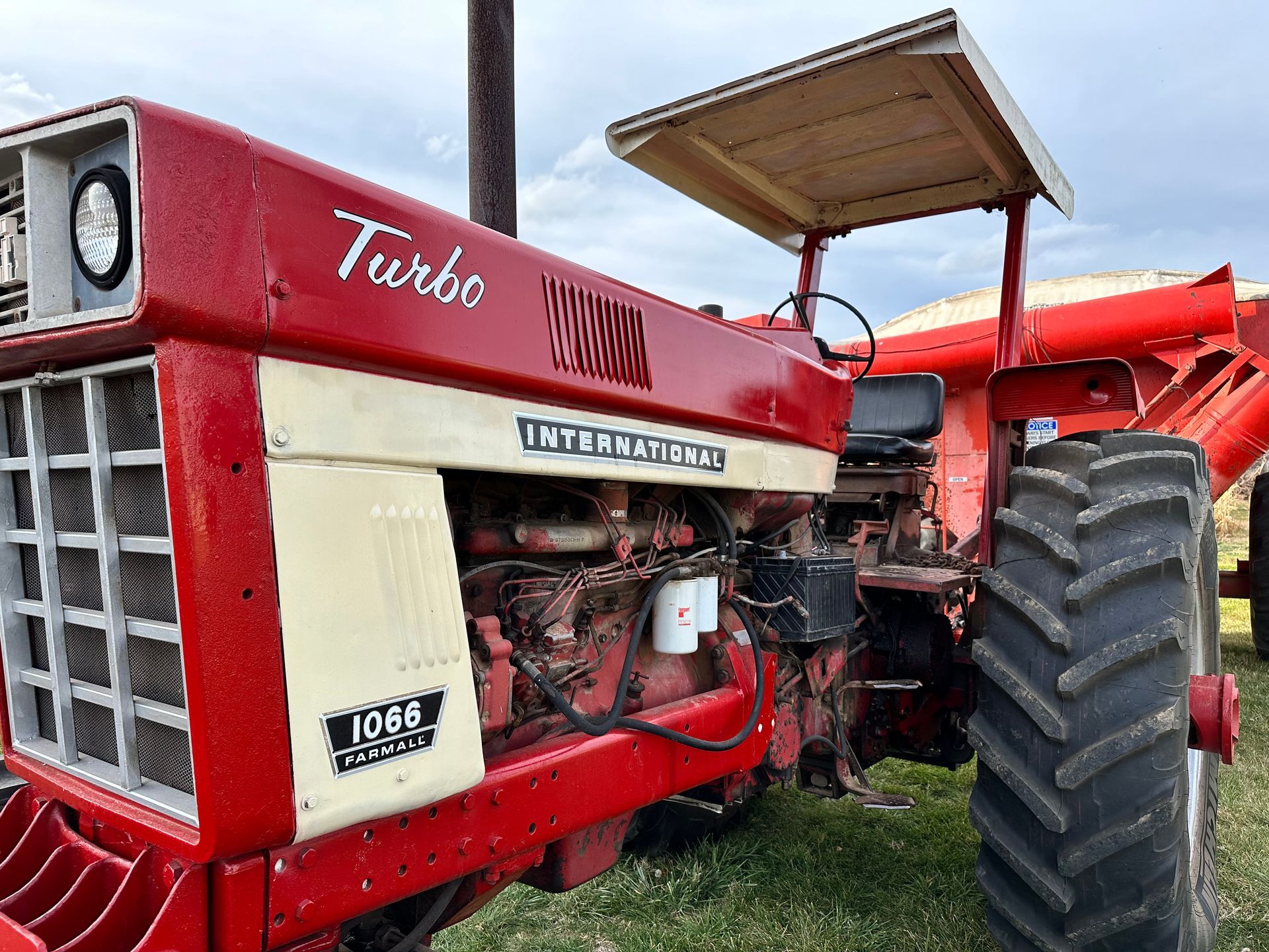 Red International 1066 Turbo tractor with a white roof, standing outdoors.