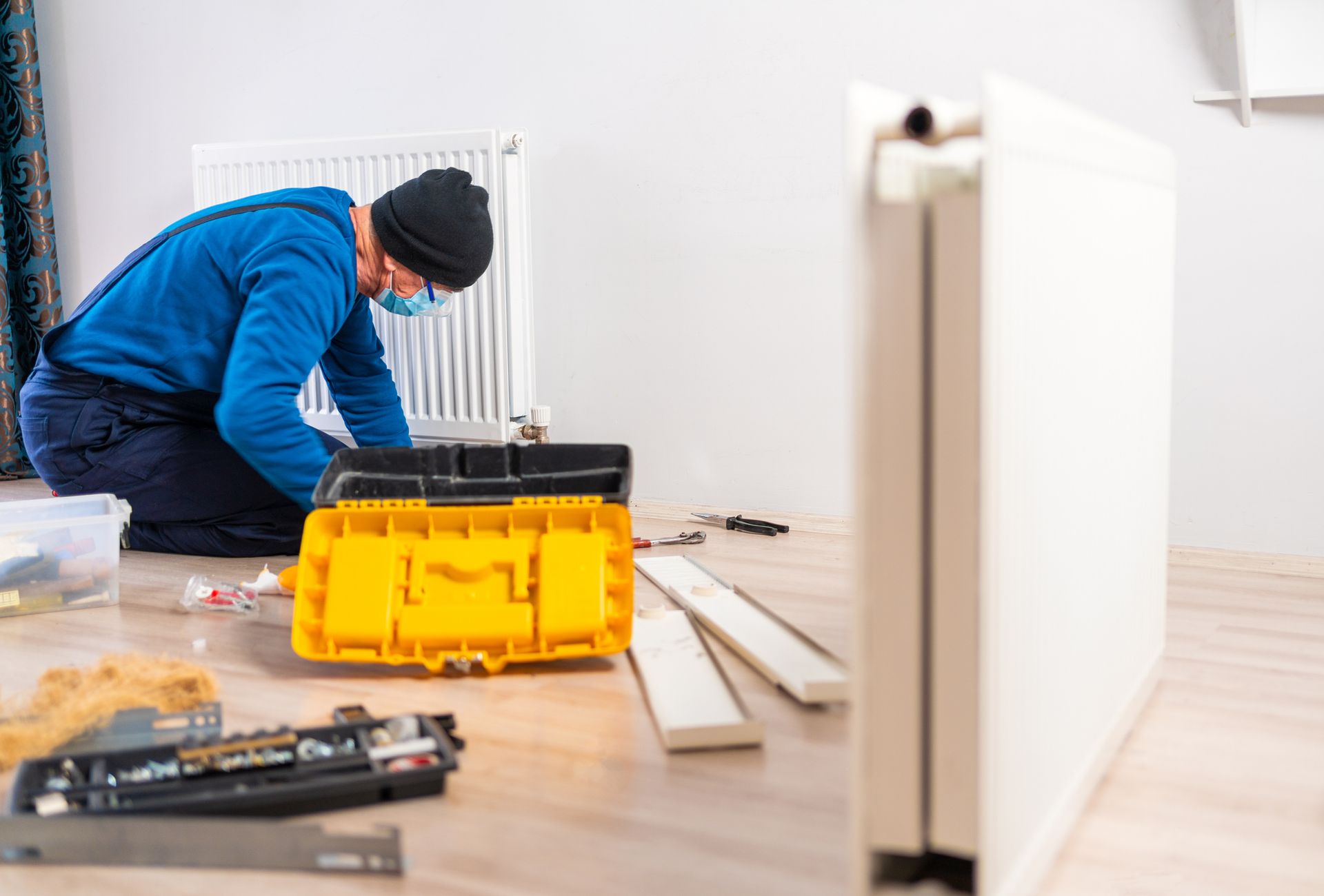 A Man Is Kneeling On The Floor Fixing A Radiator - Gulfport, MS - McGuffee's Air Conditioning & Heating A Man Is Kneeling On The Floor Fixing A Radiator - Gulfport, MS - McGuffee's Air Conditioning & Heating