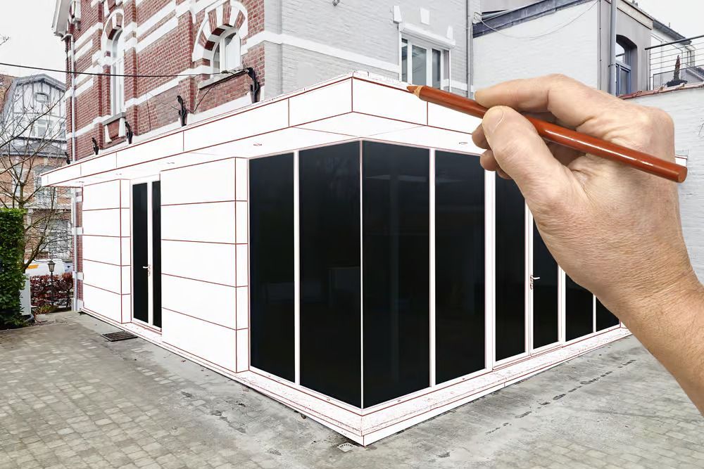 Main tenant un crayon au-dessus d'une maquette de façade de bâtiment avec des panneaux de devanture noirs