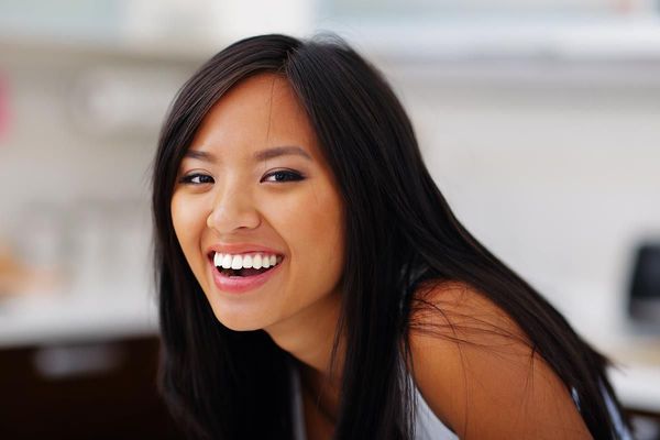 A woman with long black hair is smiling and looking at the camera