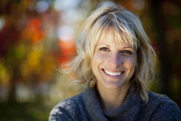 A woman in a grey sweater is smiling for the camera.
