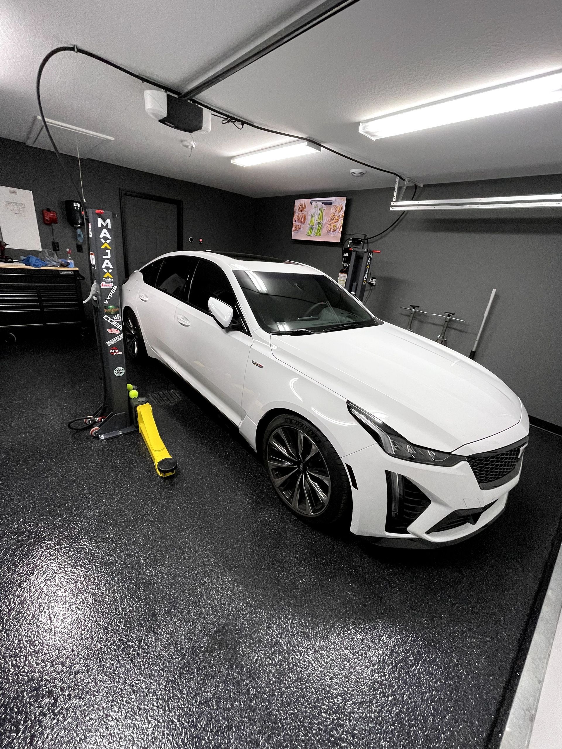 White sedan in a sleek gray garage with glossy black floors and overhead lighting