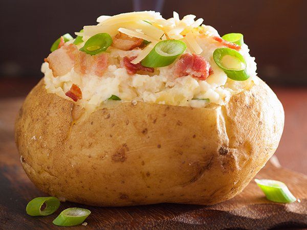 A baked potato filled with rice , cheese , bacon and green onions.