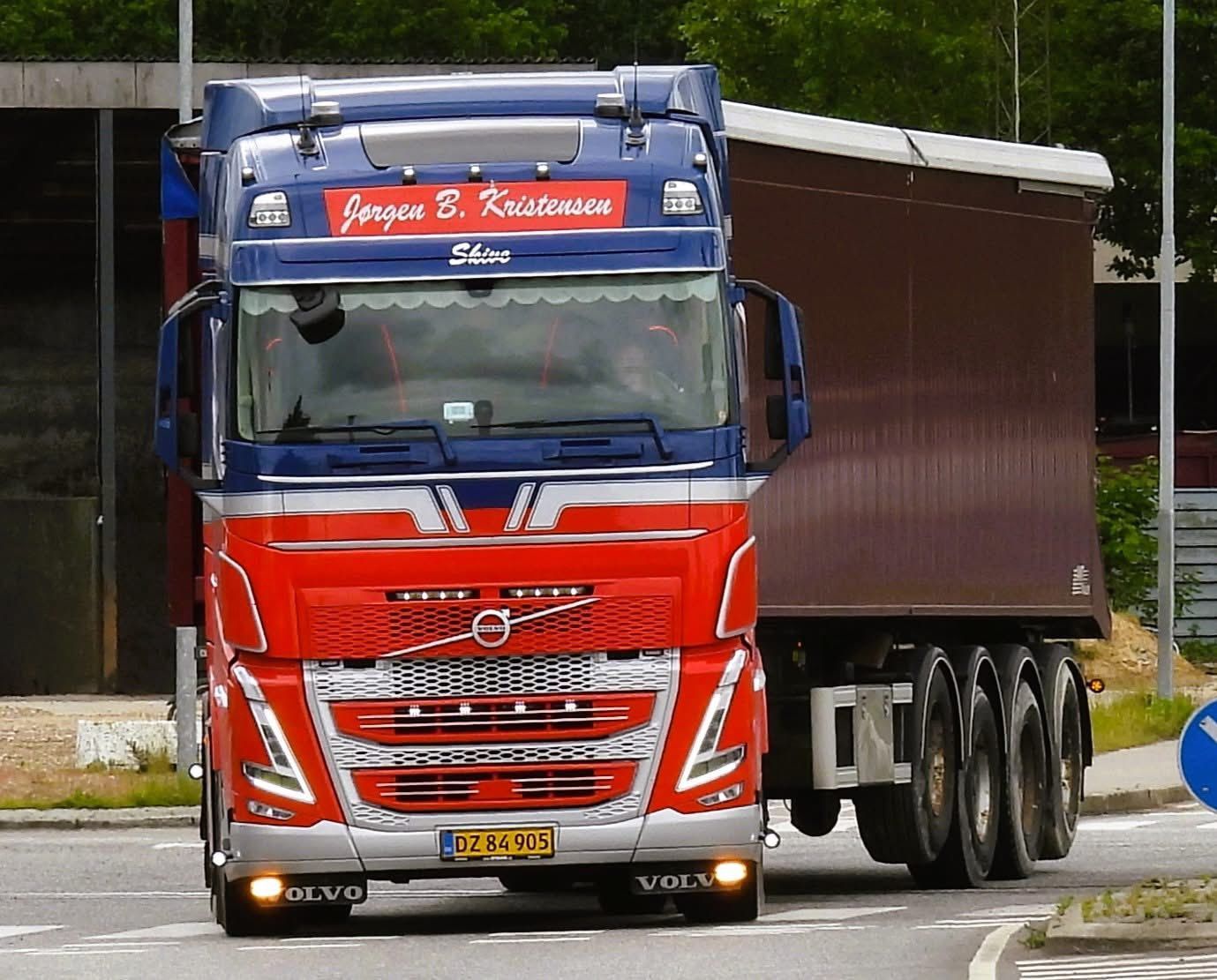 Rød Volvo semitrailer med anhænger kører på en vej, set forfra.