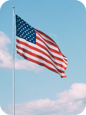 American flag waving on a flagpole against a blue sky with clouds