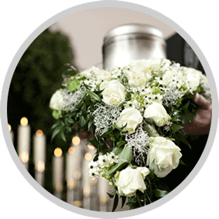 White rose and greenery bouquet held in front of candles and a silver urn
