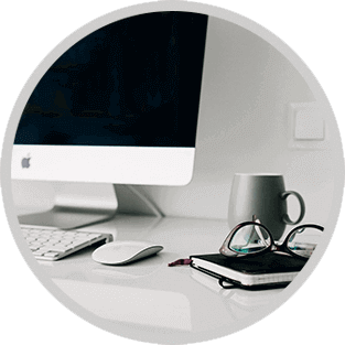 Minimal white desk with iMac, keyboard, mouse, mug, and notebook in a tidy home office.