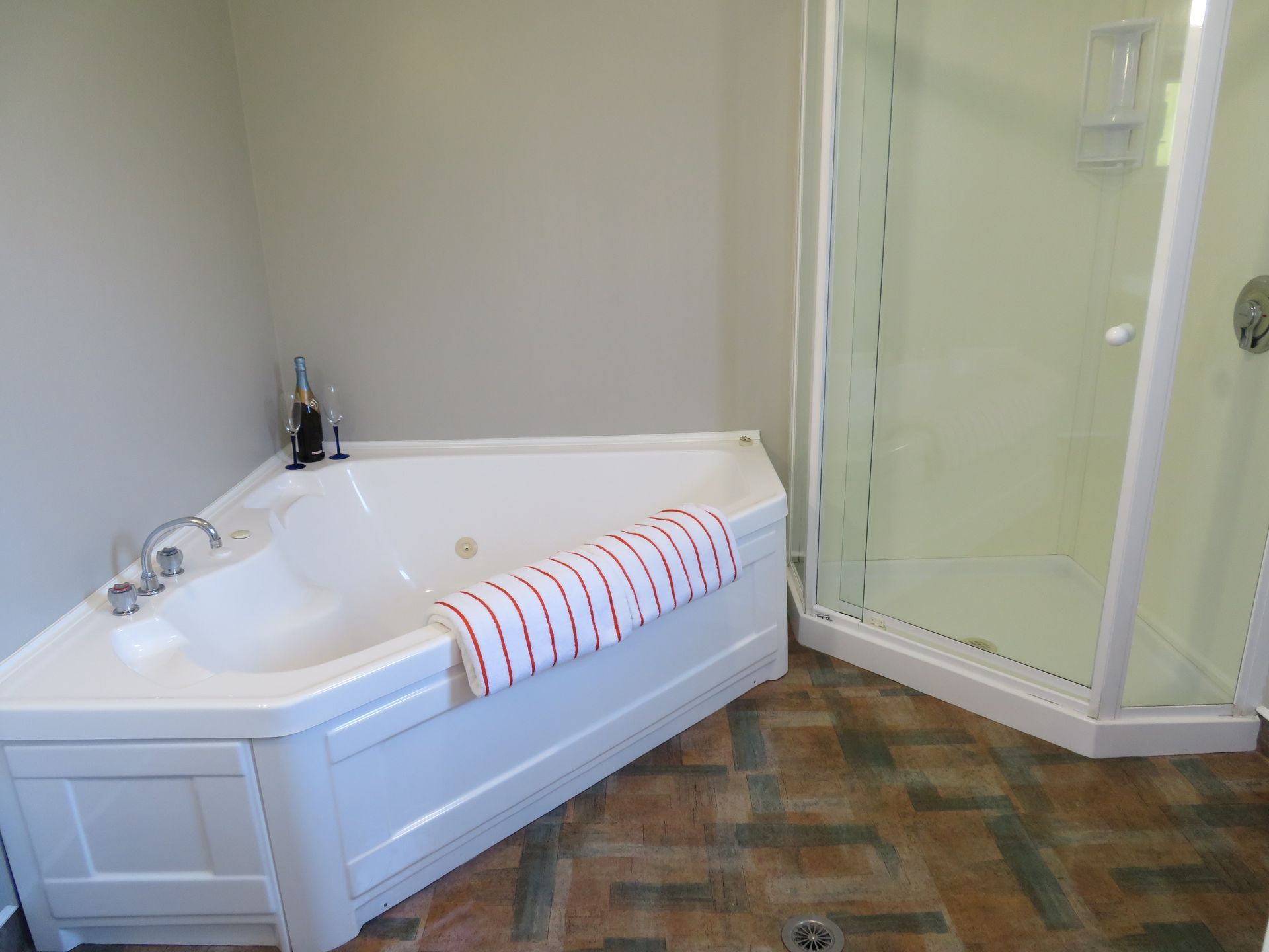 Bathroom with a white walk-in tub, glass shower enclosure, and patterned tile floor.
