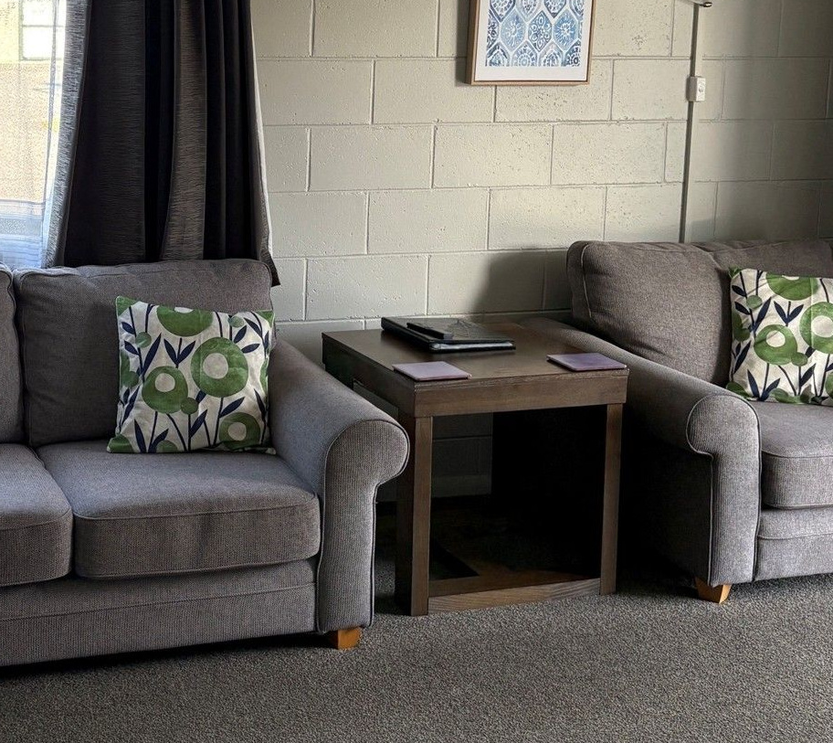 Living room with two gray sofas, patterned pillows, and a small wooden side table between them.