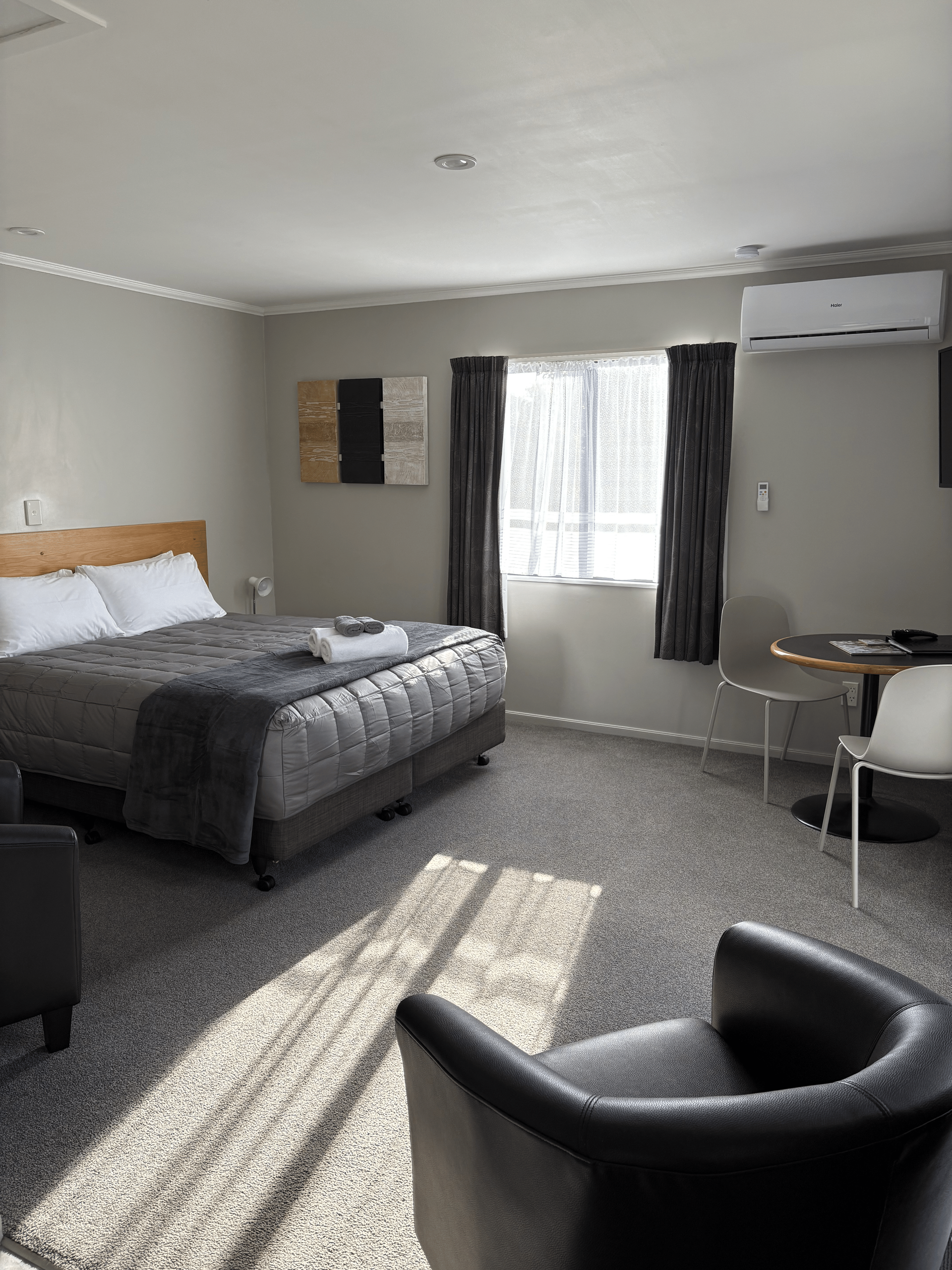 Small bedroom with a bed, chair, desk, window, and wall-mounted air conditioner.