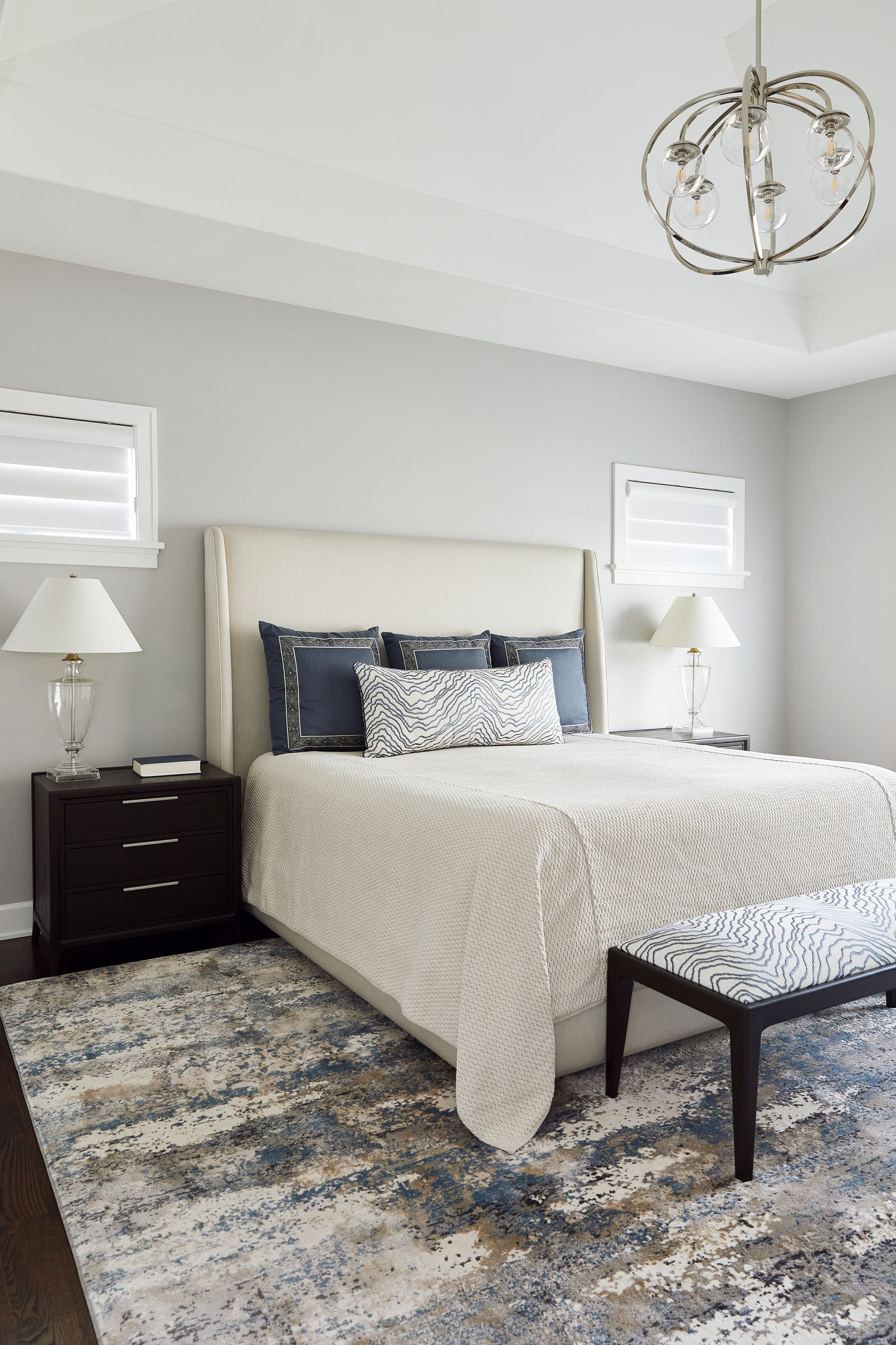 A bedroom with a bed , nightstand , lamp and rug.