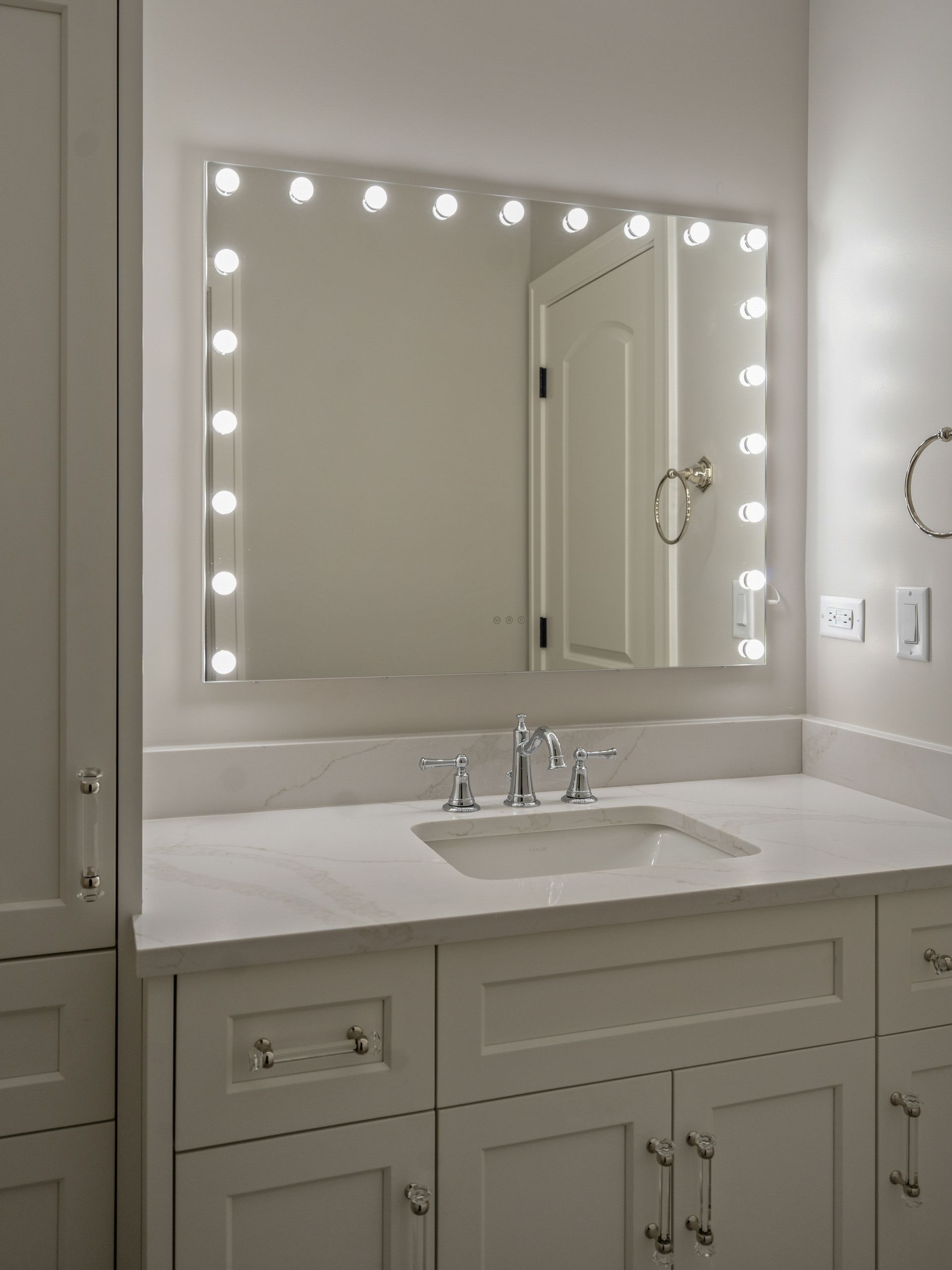 A bathroom with a sink and a mirror with lights on it.