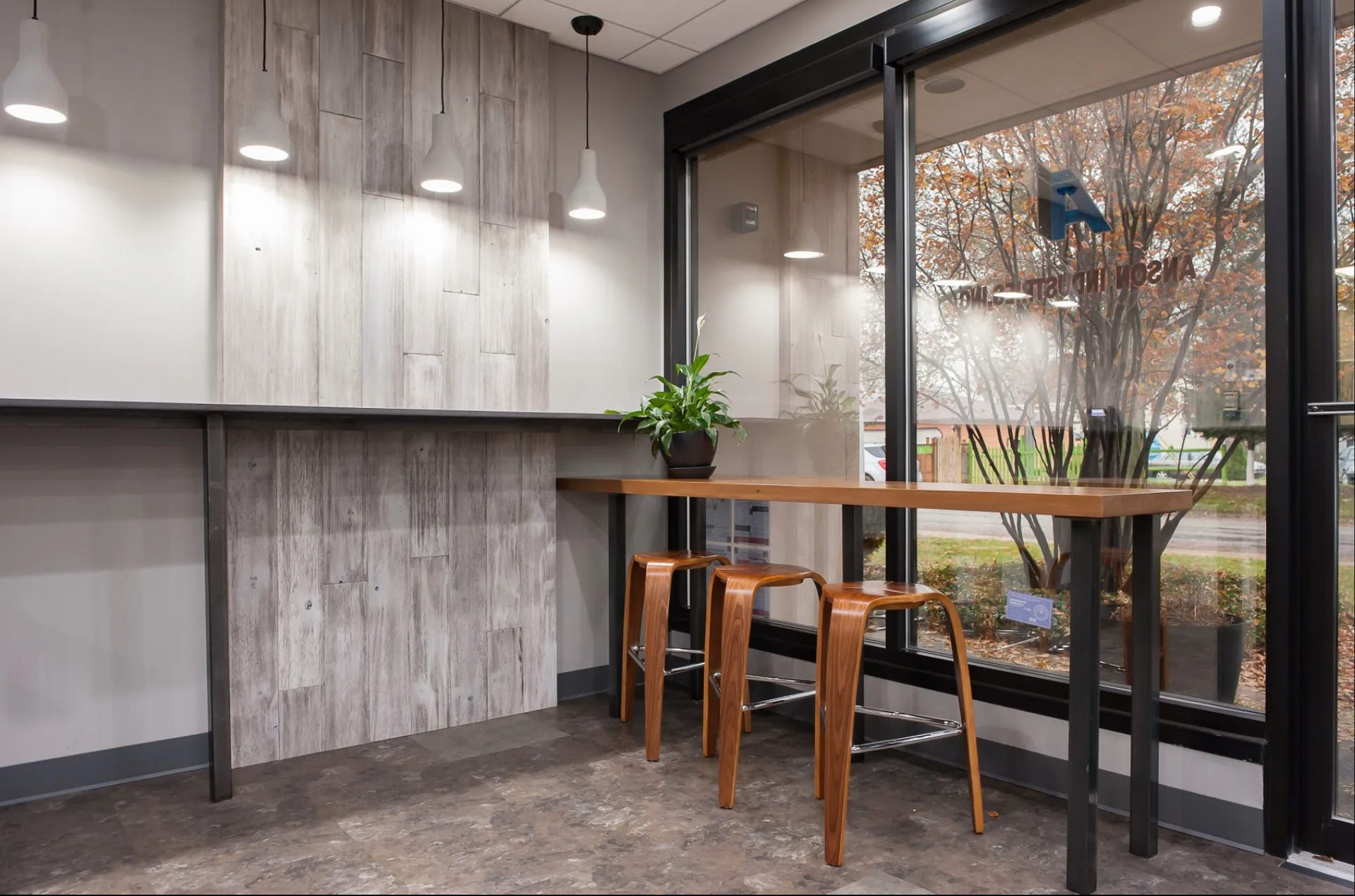 A room with a table and stools in front of a window.