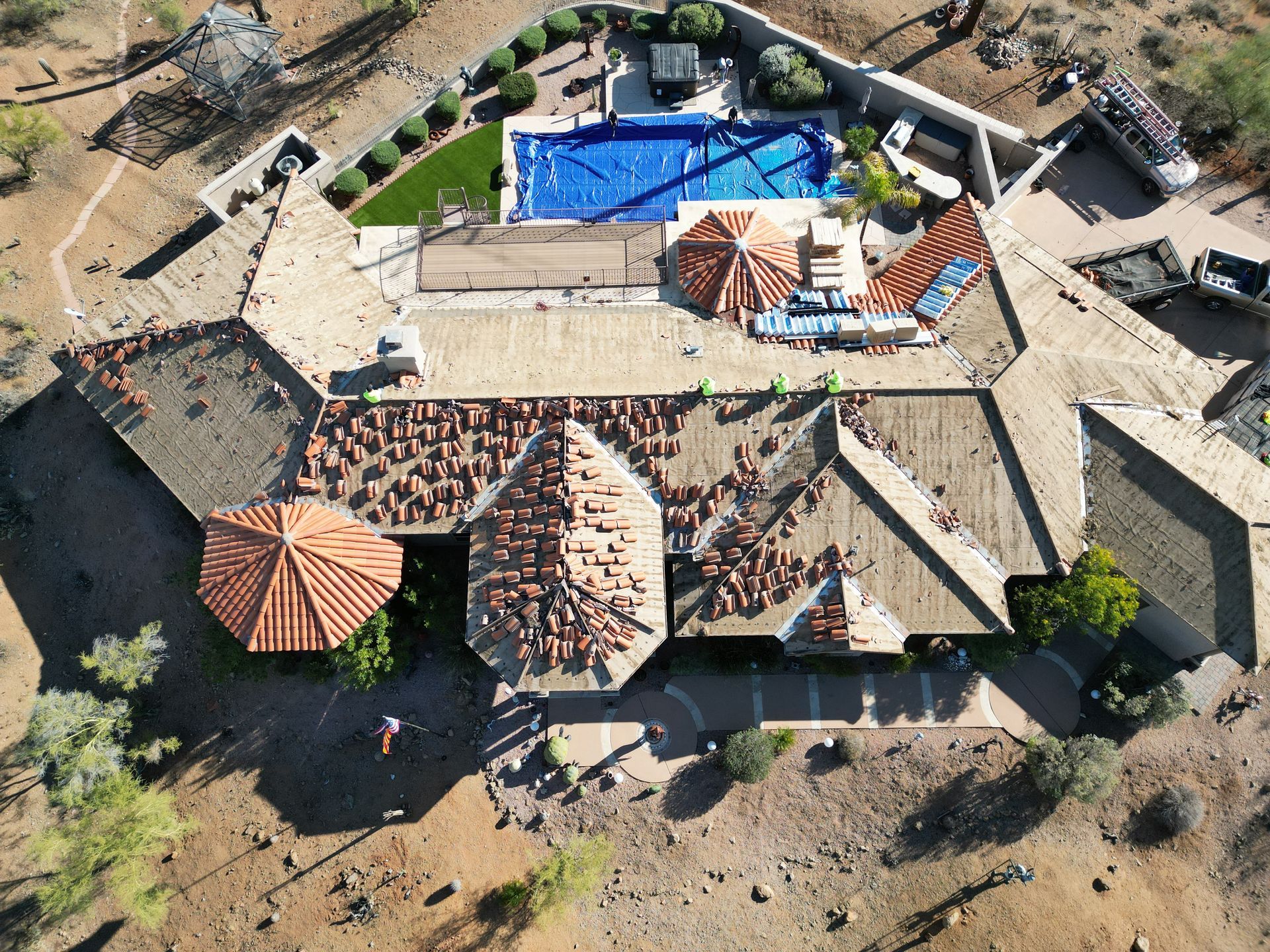 Aerial view of a resort patio with tables, umbrellas, lounge chairs, and a blue pool.
