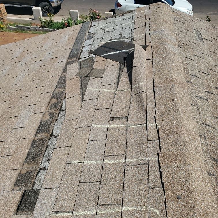 Roof replacement in progress on a house; workers on roof and ground, debris and truck present.