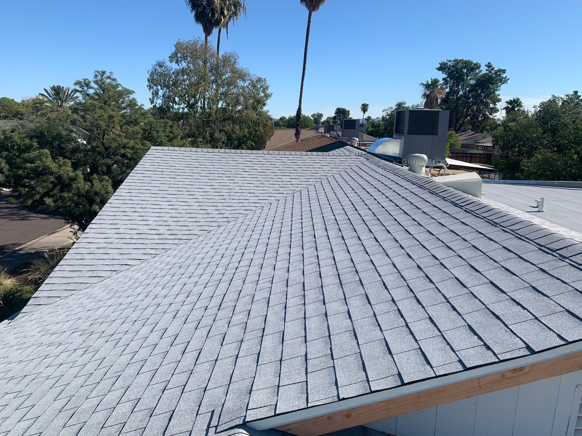 Roofers replacing clay tiles on a house roof under a clear blue sky.