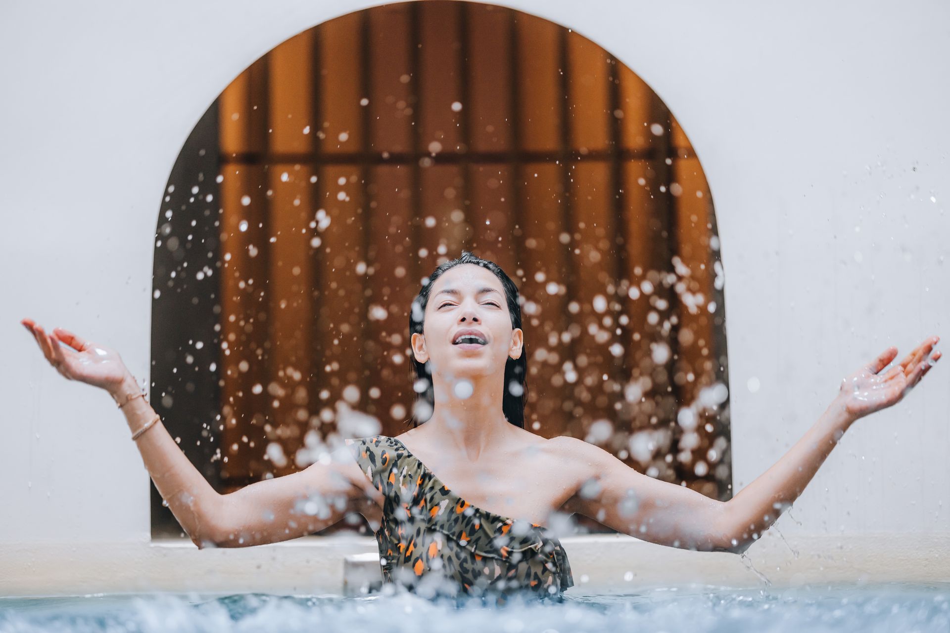 Une femme en maillot de bain éclabousse l'eau dans une piscine.