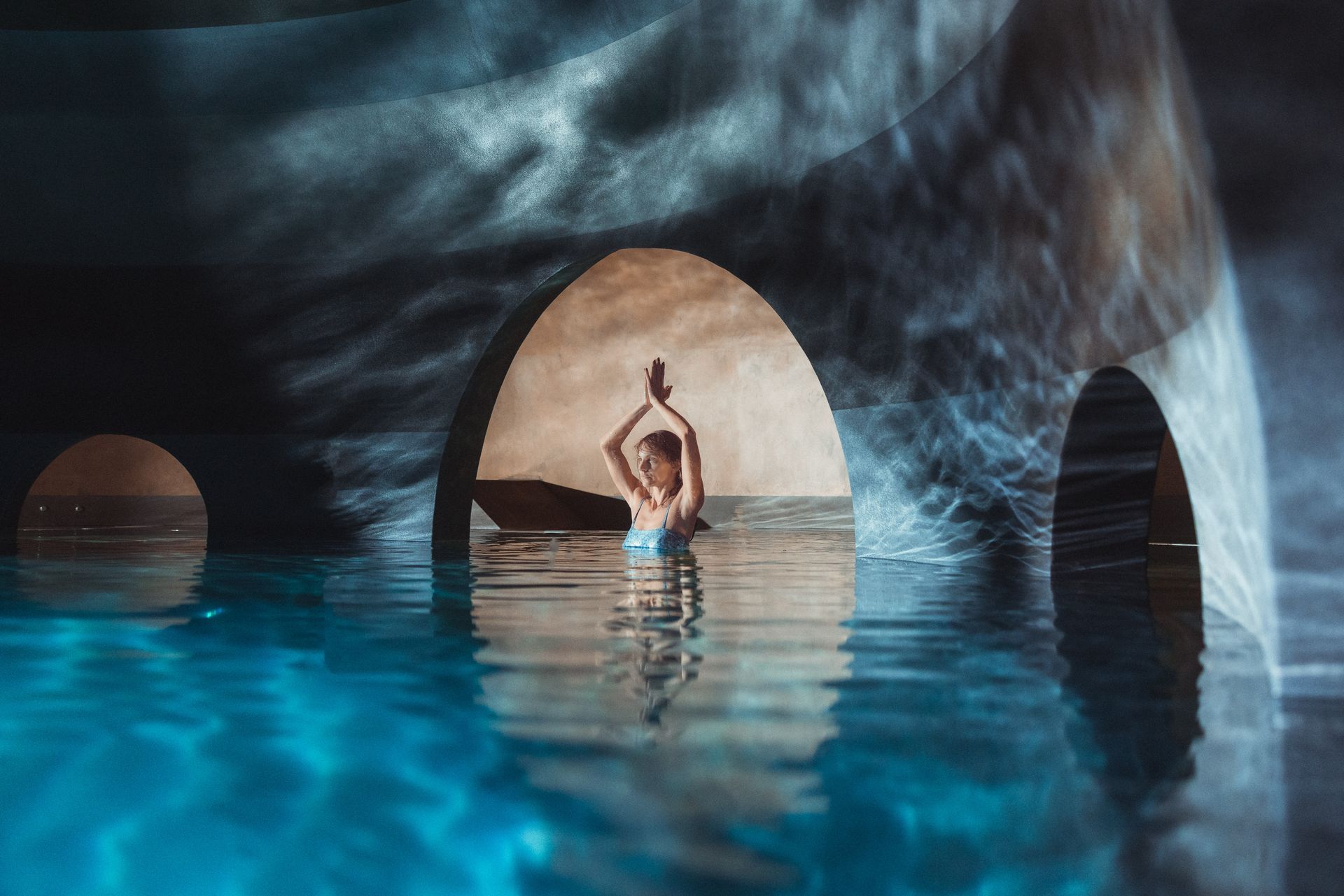 Une femme médite dans un bassin d'eau dans une grotte.
