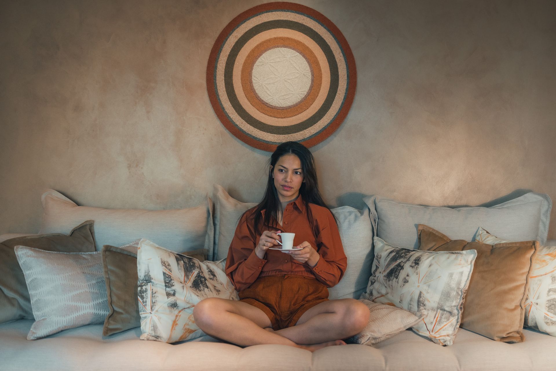 Une femme est assise sur un canapé tenant une tasse de café.