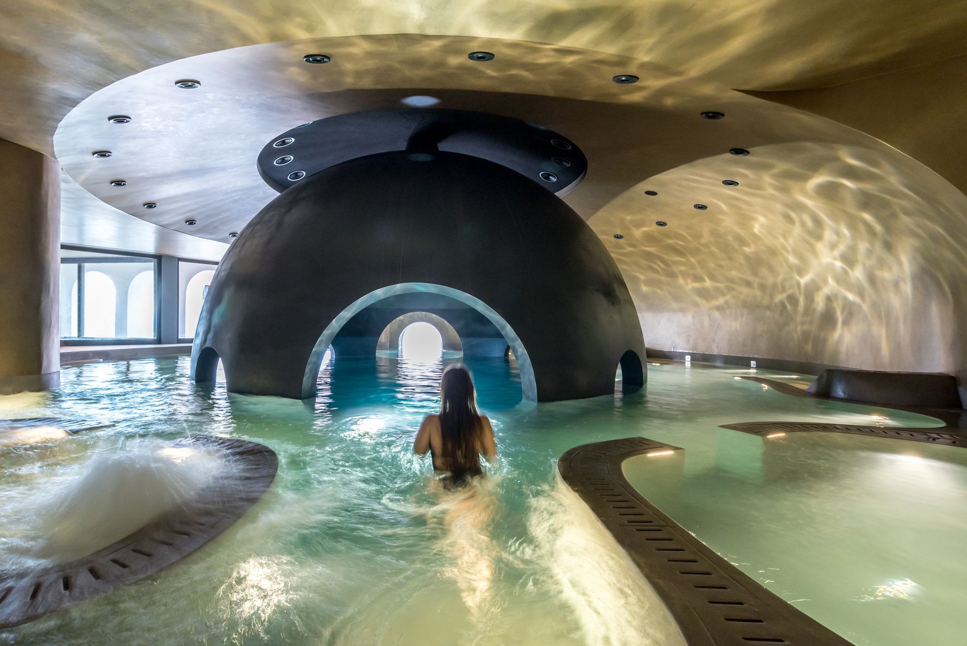 Une femme nage dans une grande piscine intérieure.