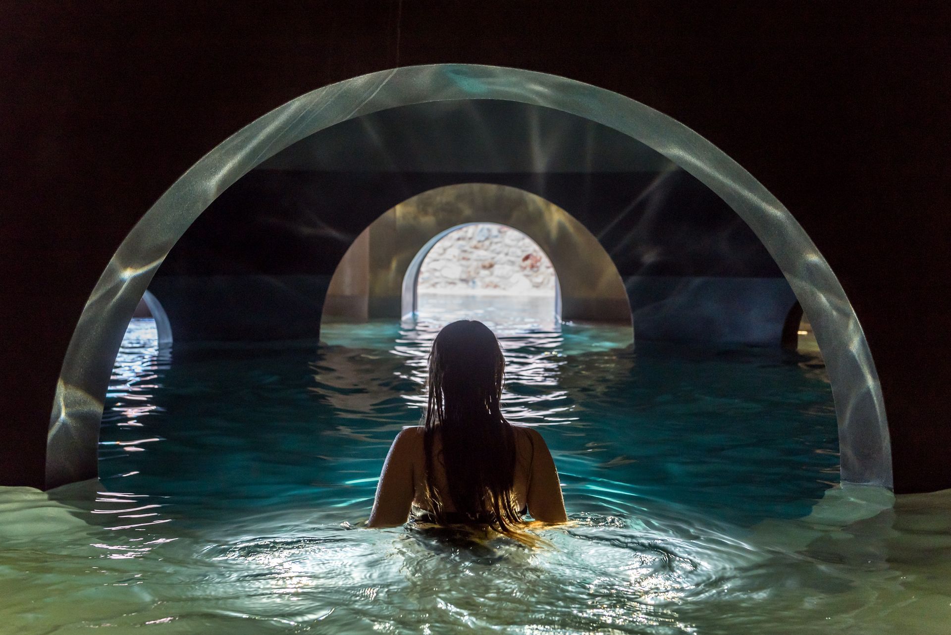 Une femme nage dans un tunnel dans une piscine.