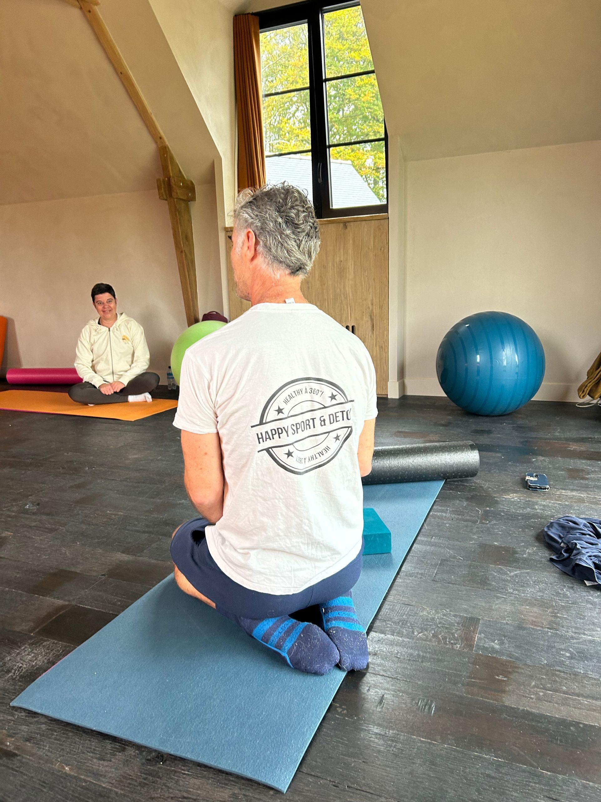 Un homme est agenouillé sur un tapis de yoga dans une salle de sport.