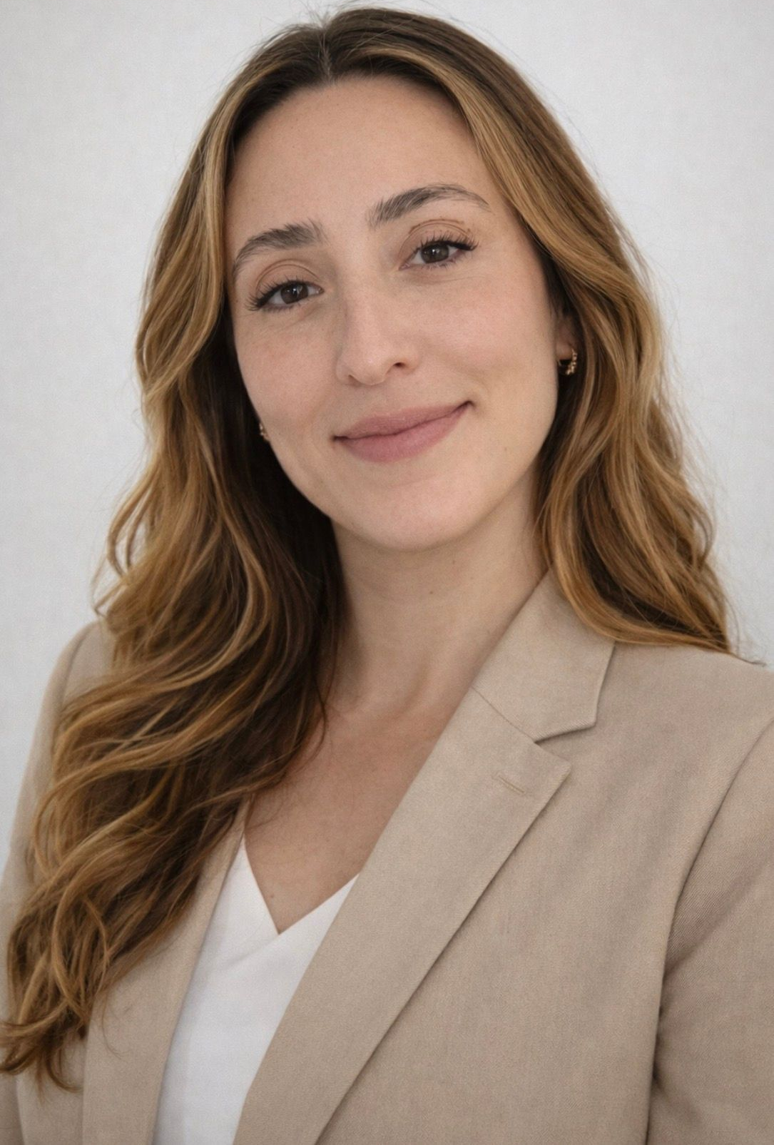 Portrait of a smiling woman in a beige blazer and white top against a light background