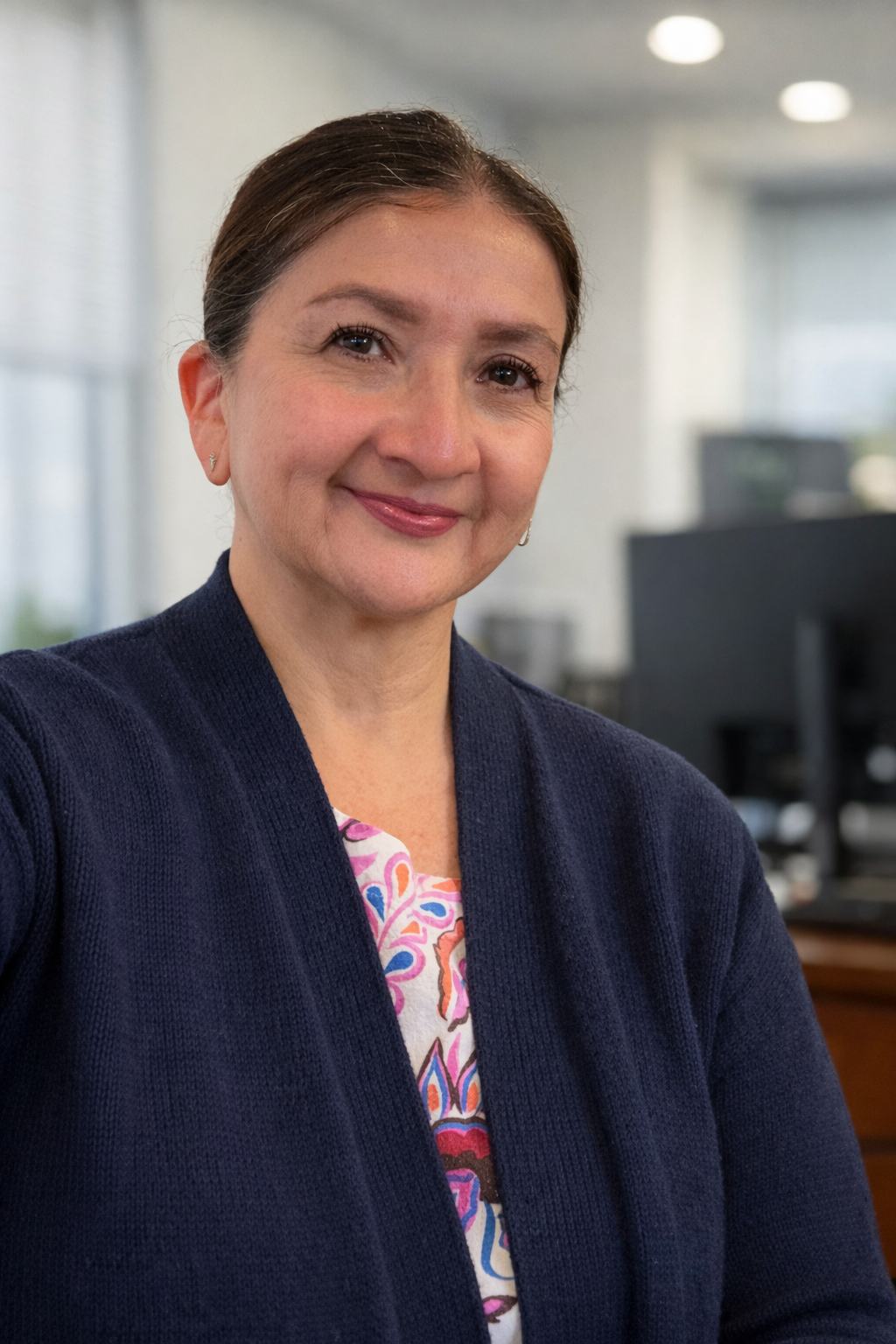 Portrait of a smiling woman in a navy cardigan in an office setting