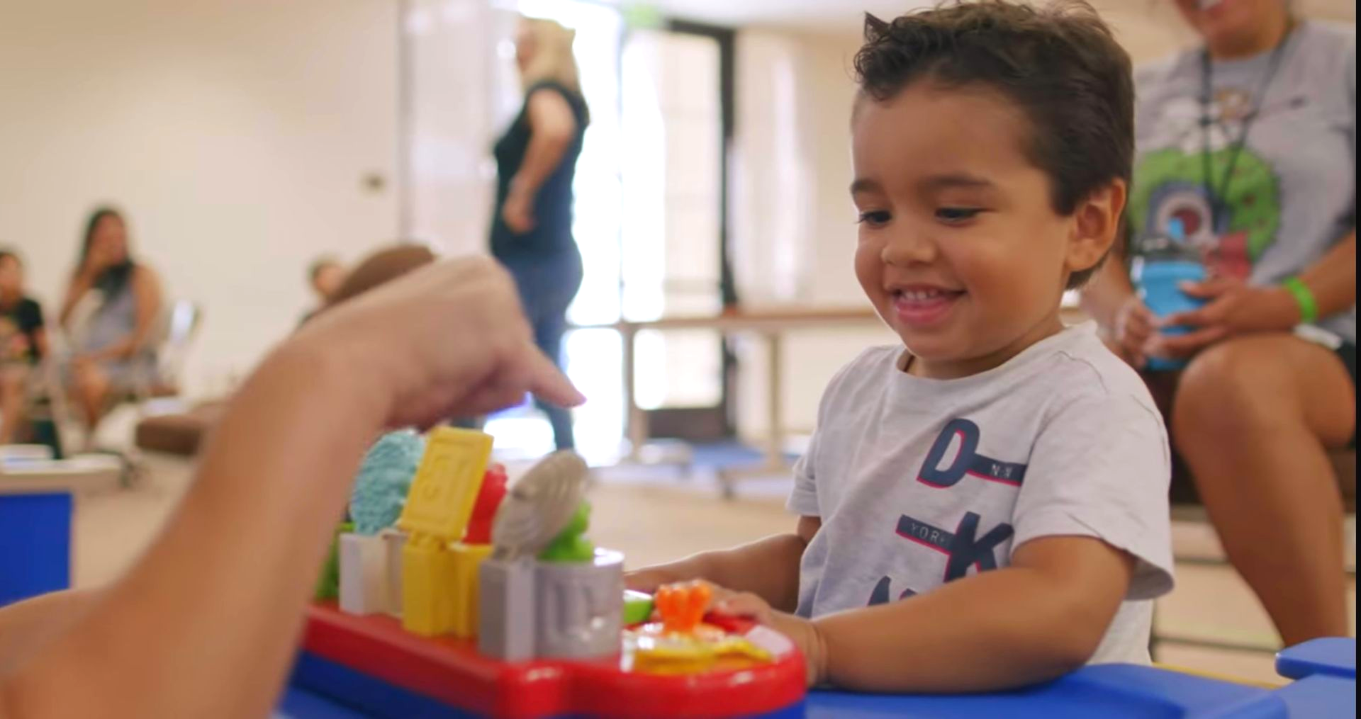 Smiling child playing with colorful blocks at a table in a bright playroom
