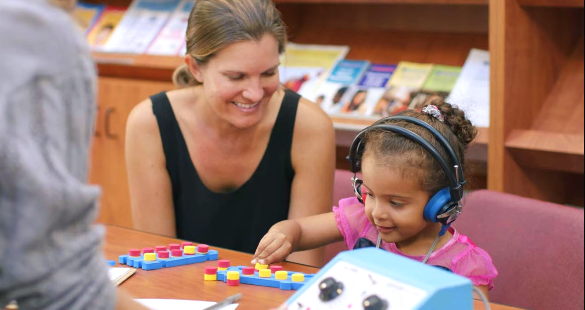 Woman and child smiling and playing with colorful toys at a table in a library