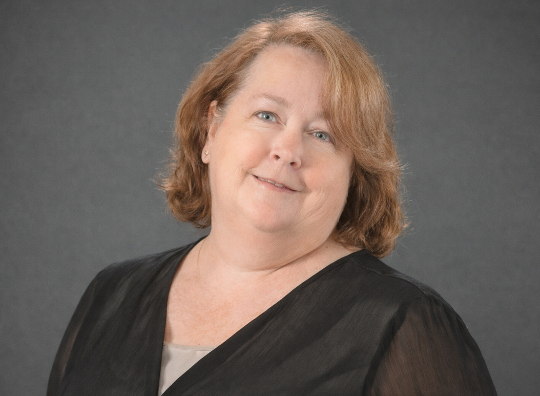 Smiling person in a black top against a plain gray background