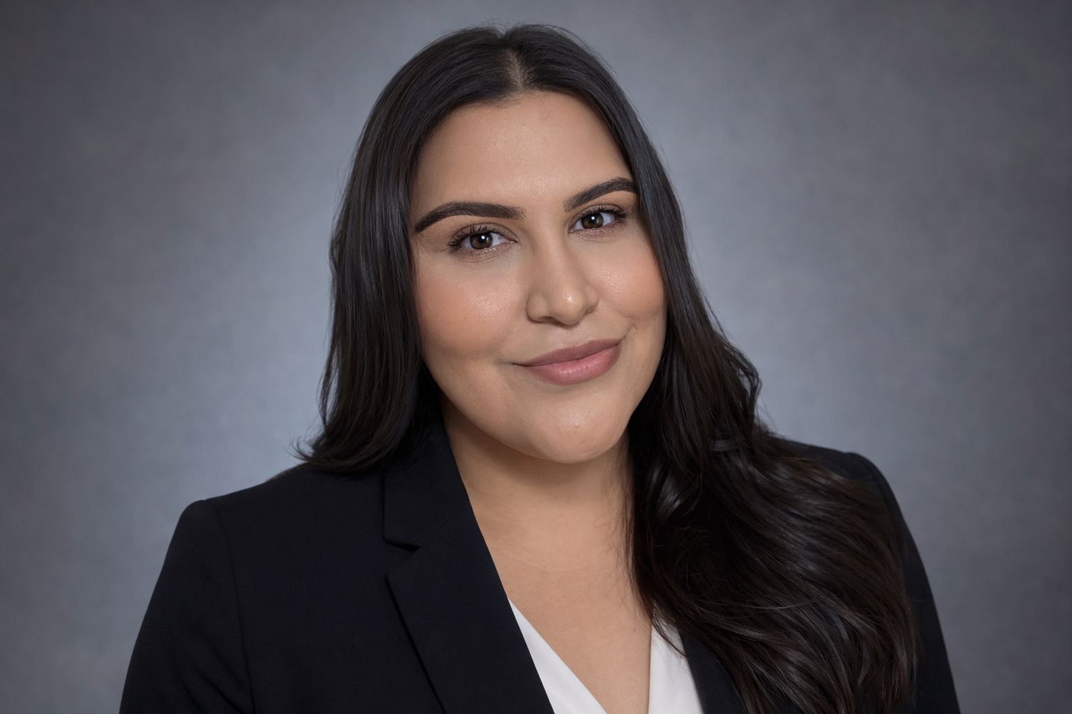 Portrait of a woman in a black blazer against a gray studio background