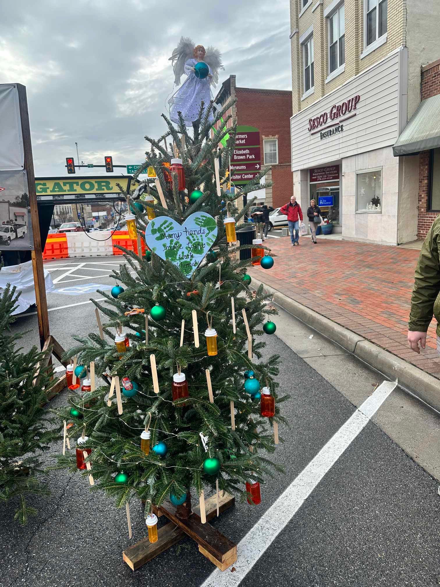 A christmas tree is sitting in a parking lot in front of a building.