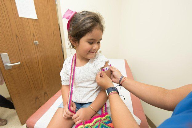 A little girl is getting a vaccine from a doctor.