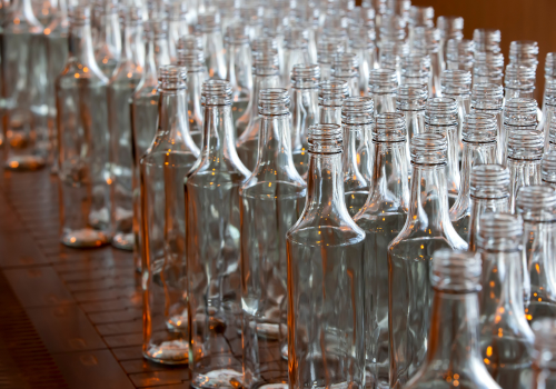 Rows of empty glass bottles with narrow necks, likely for filling.