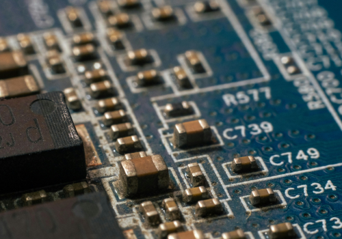 A close-up of a blue printed circuit board populated with various small, brown surface-mount electronic components.